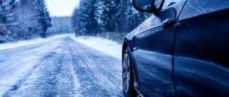 black car iced road surrounded by trees covered with snow