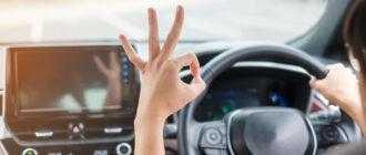 woman showing ok sign during driving car road hand controlling steering wheel electric modern automobile journey trip safety transportation concepts