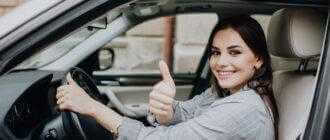 beautiful young latin woman driving her brand new car showing her thumb up