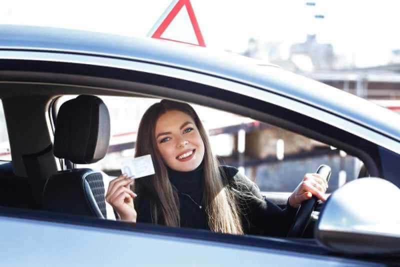 joyful girl driving training car with drivers license card her hands 1
