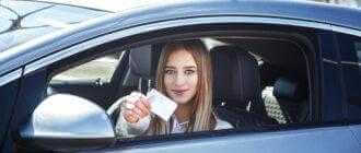 joyful girl driving training car with drivers license card her hands